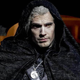 Henry Cavill wears a black cloak and his wolf medallion as Geralt in The Witcher TV series.